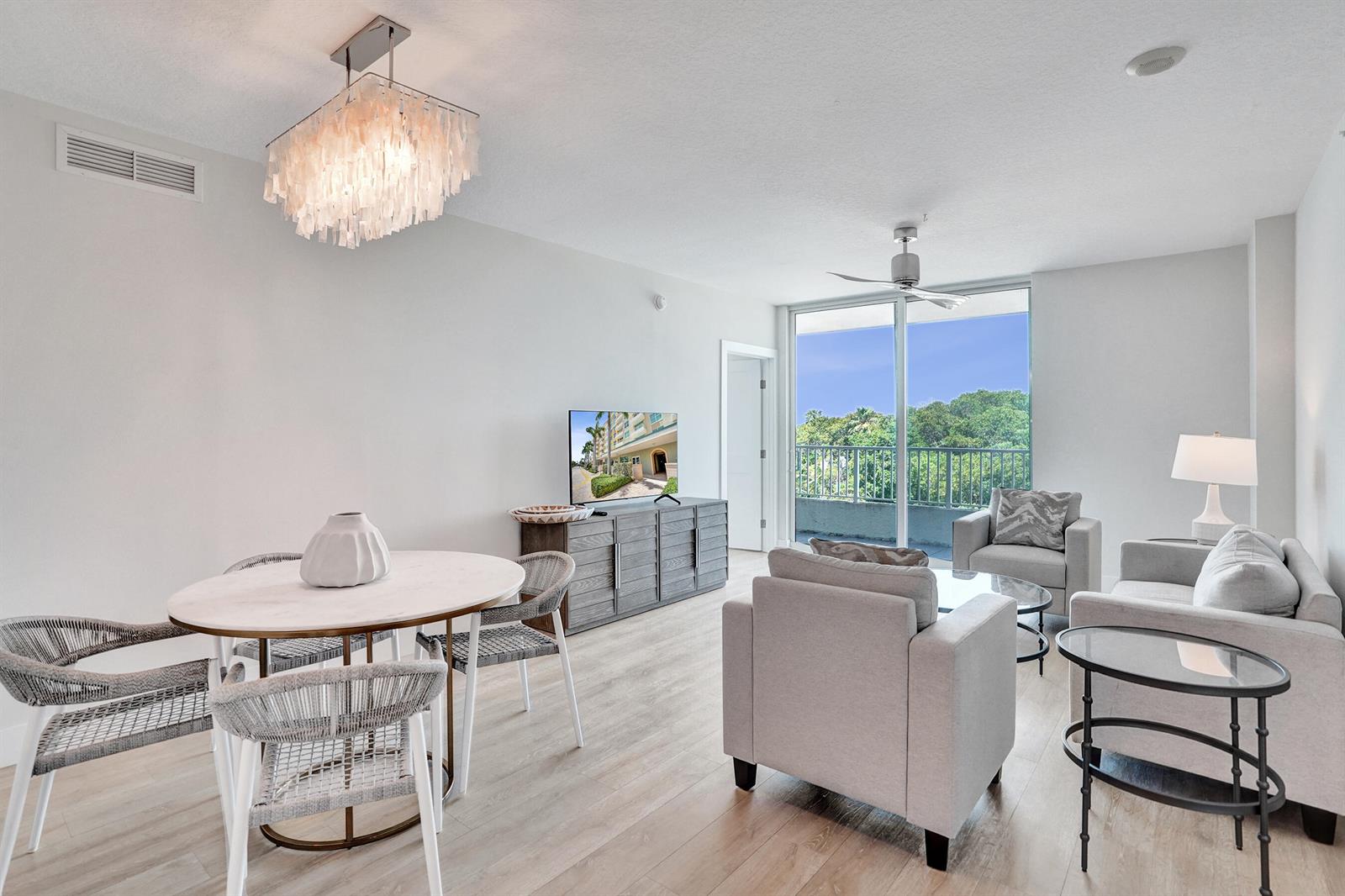 A bright living and dining area features light wood floors, a chandelier, and a balcony — 700 E Boynton Beach Boulevard # 406, Boynton Beach FL 33435, BOYNTON BEACH, FL