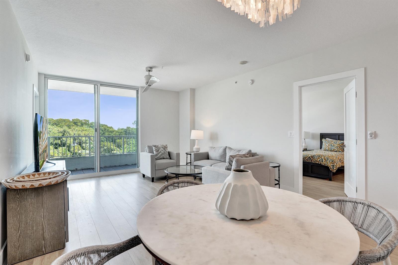 A bright living and dining area features light wood floors, a balcony, and white walls — 700 E Boynton Beach Boulevard # 406, Boynton Beach FL 33435, BOYNTON BEACH, FL