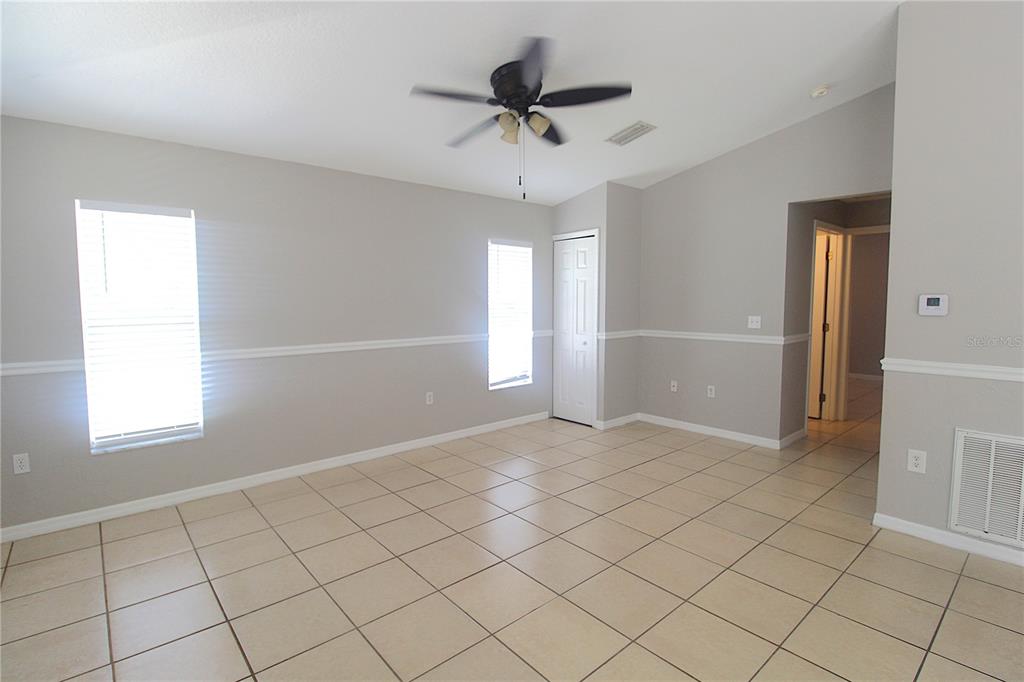An empty room features light gray walls, tile flooring, a ceiling fan, and two windows — 5445 ALTOONA STREET, SARASOTA, FL