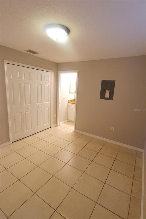 A room with light-colored tile flooring, a white closet, and an electrical panel on the wall — 5445 ALTOONA STREET, SARASOTA, FL