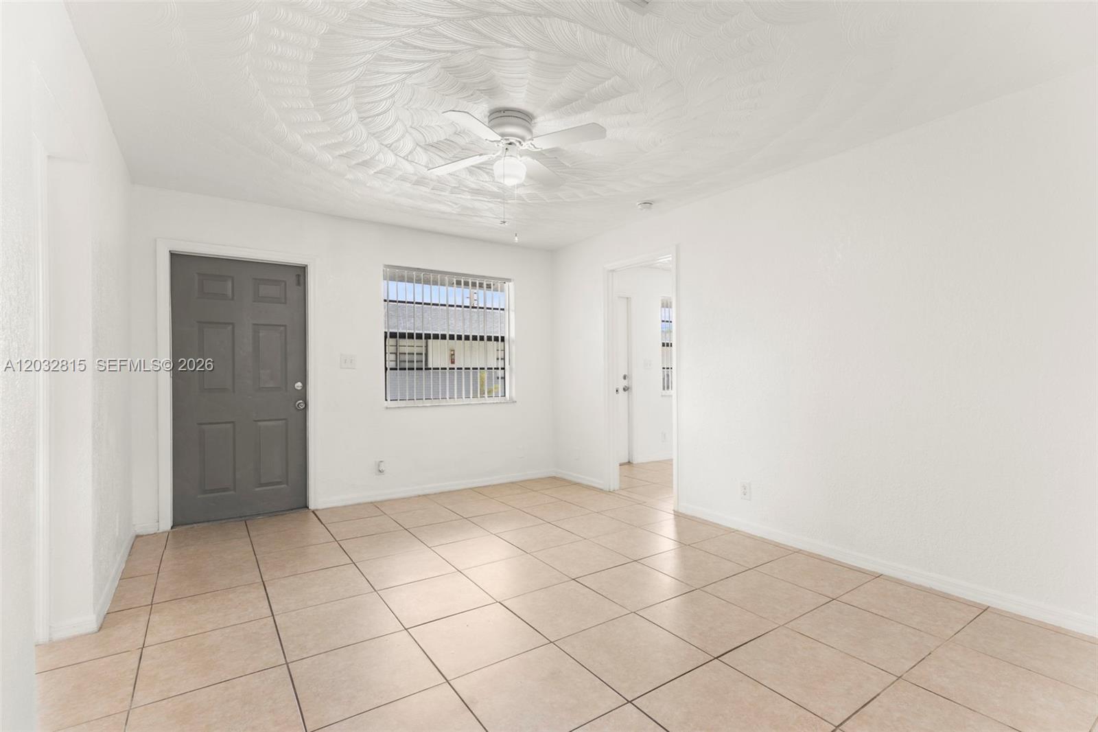 A room with white walls, light tile flooring, a ceiling fan, and a gray door — 4120 SW 19th St, West Park FL 33023, WEST PARK, FL