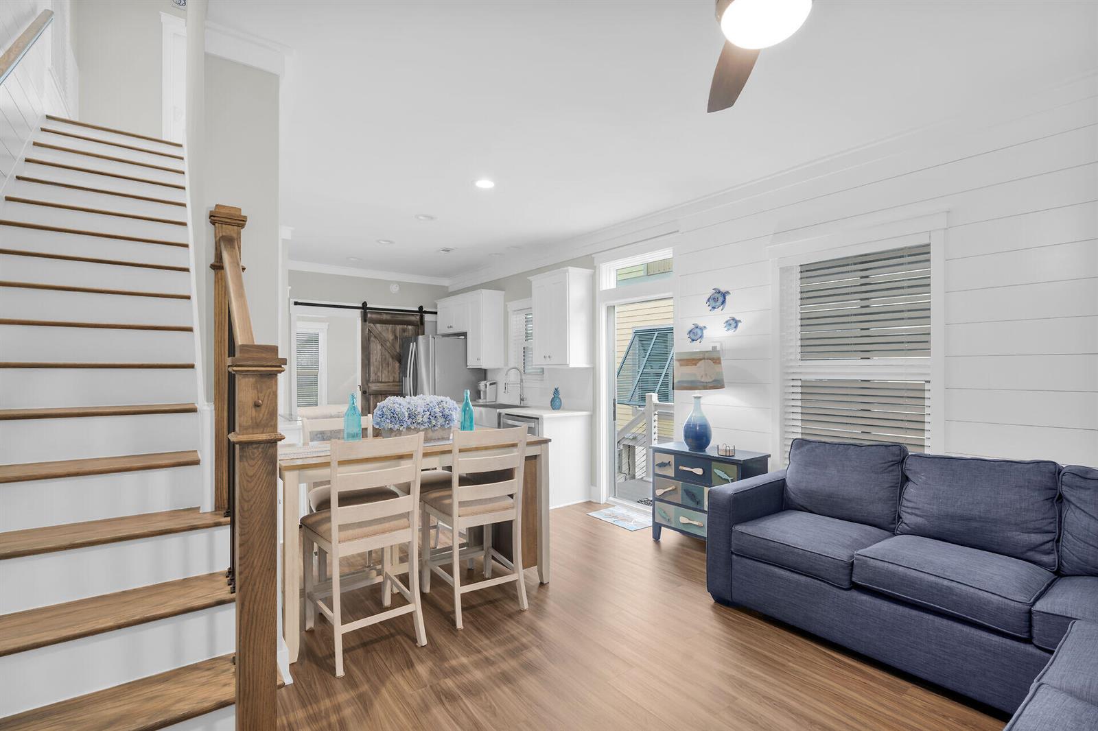 A living room and kitchen area with a wooden staircase, blue sofa, and dining table — 101 11th Street # 19, Marathon FL 33050, MARATHON, FL