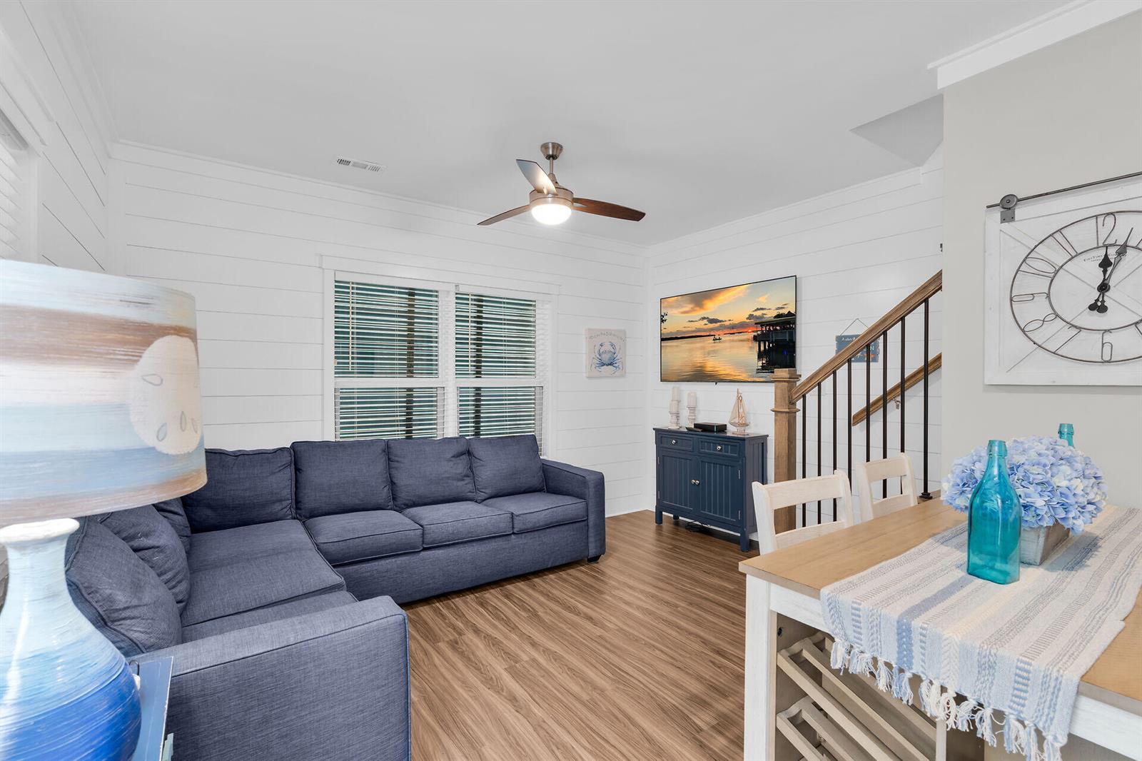 A living room features a blue sectional sofa, white shiplap walls, and a wooden staircase — 101 11th Street # 19, Marathon FL 33050, MARATHON, FL