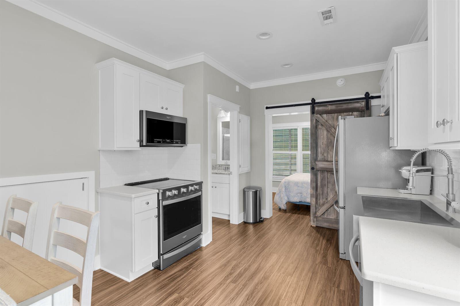 A kitchen with white cabinets, stainless steel appliances, and a sliding barn door to a bedroom — 101 11th Street # 19, Marathon FL 33050, MARATHON, FL