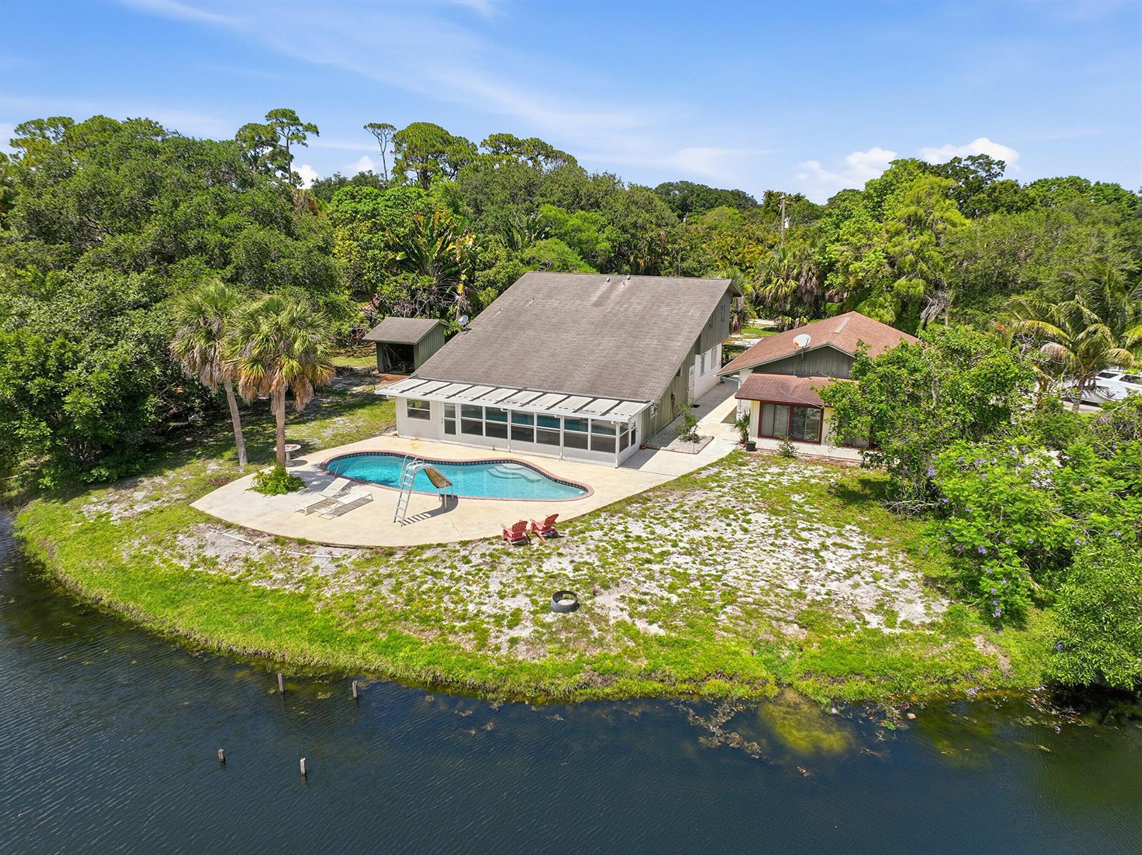 An aerial view of a house with a swimming pool situated next to a lake — 7689 Lawrence Road, Boynton Beach FL 33436, BOYNTON BEACH, FL