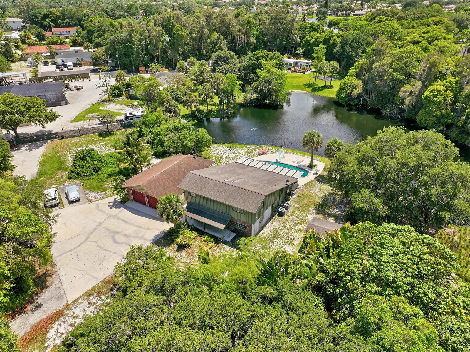 An aerial view of a house with a detached garage, pool, and pond — 7689 Lawrence Road, Boynton Beach FL 33436, BOYNTON BEACH, FL