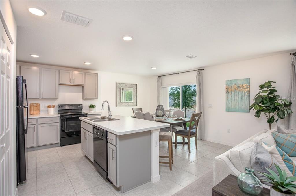 A kitchen with gray cabinets, a central island, and an adjacent dining area with tile flooring — 426 OHIO LANE, POINCIANA, FL