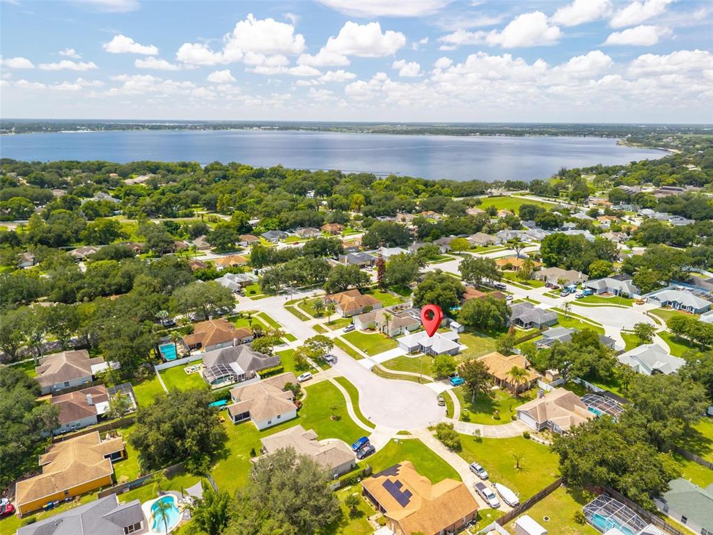 An aerial view shows a suburban neighborhood with houses, green lawns, and a large lake — 1025 GREEN RIDGE COURT, MINNEOLA, FL