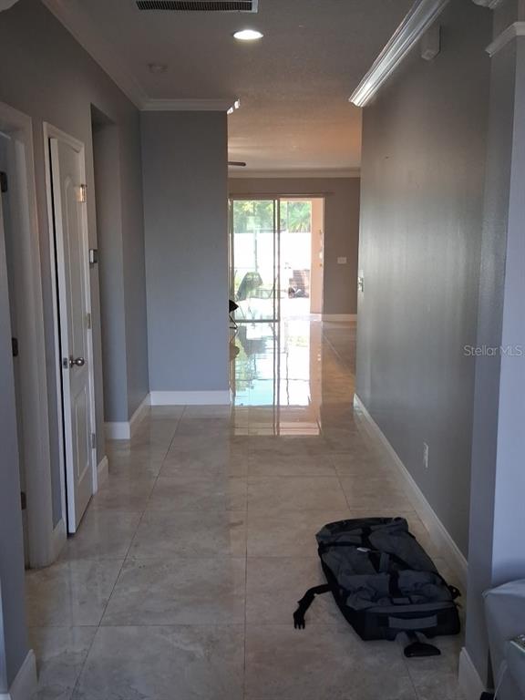 A hallway with light-colored tile flooring leads toward a glass sliding door at the end — 405 BLAKELY COURT, RUSKIN, FL