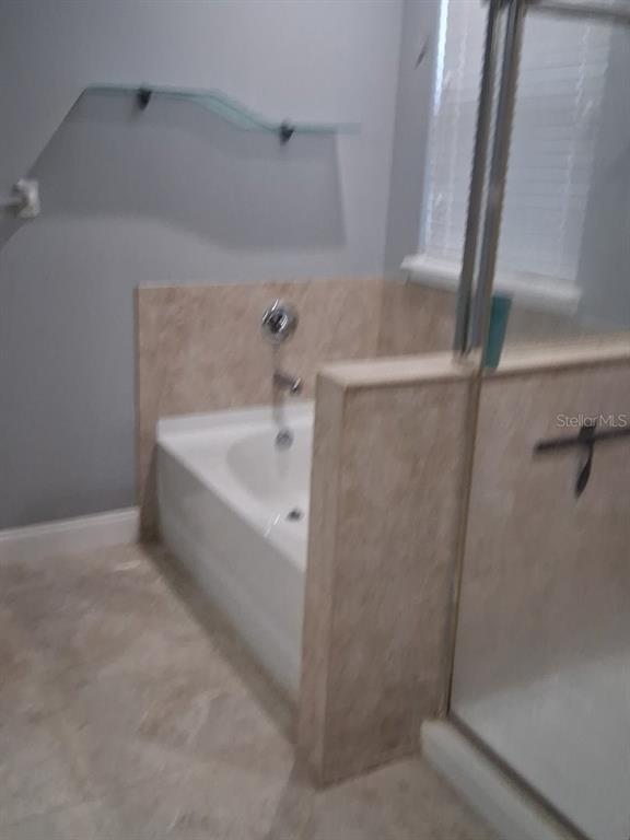 A bathroom features a white soaking tub with tan tile surround and a glass shelf — 405 BLAKELY COURT, RUSKIN, FL