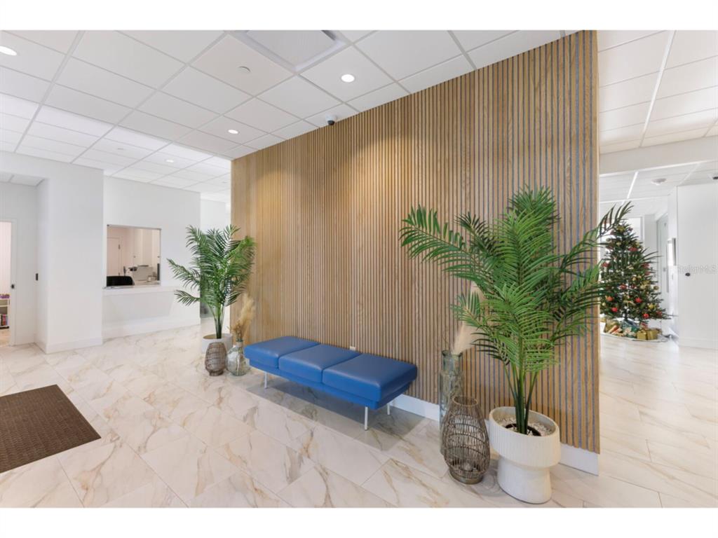 A waiting area features a blue bench against a vertical wood-slat accent wall — 1750 BENJAMIN FRANKLIN DRIVE UNIT 1D, SARASOTA, FL