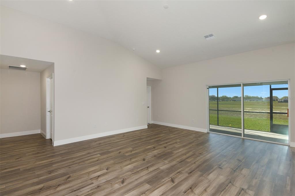 An empty room with wood-look flooring, recessed lighting, and a sliding glass door to outside — 6103 SW 97TH STREET, OCALA, FL