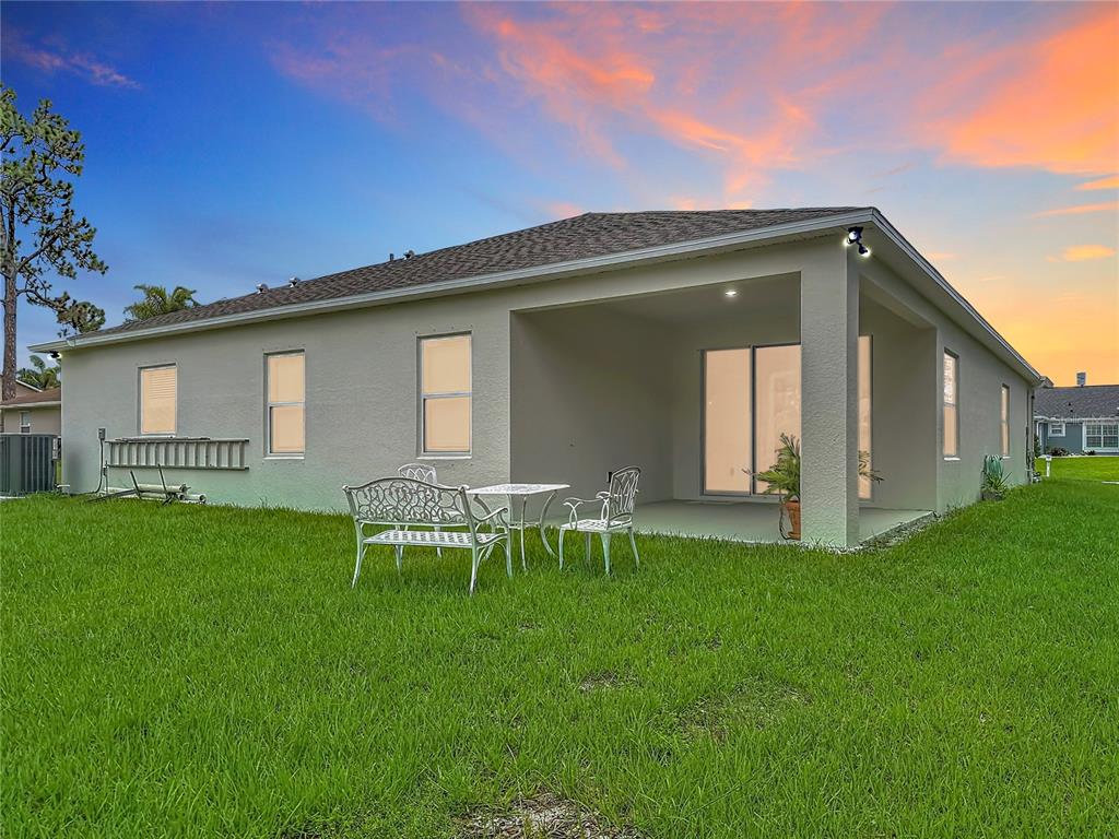 The exterior rear view of a house features a covered patio and a grassy lawn — 1342 CAMAS AVENUE NW, PALM BAY, FL