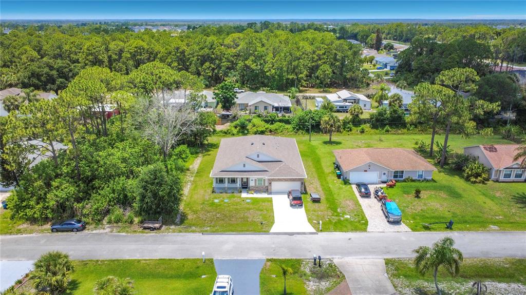An open-concept living area features a kitchen with dark cabinets, a dining set, and seating — 1342 CAMAS AVENUE NW, PALM BAY, FL