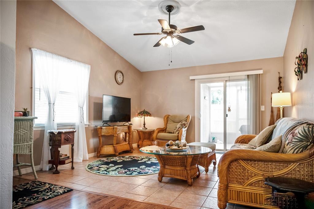 A living room features wicker furniture, tile flooring, a ceiling fan, and sliding glass doors — 2835 NORDMAN AVENUE, NEW SMYRNA BEACH, FL
