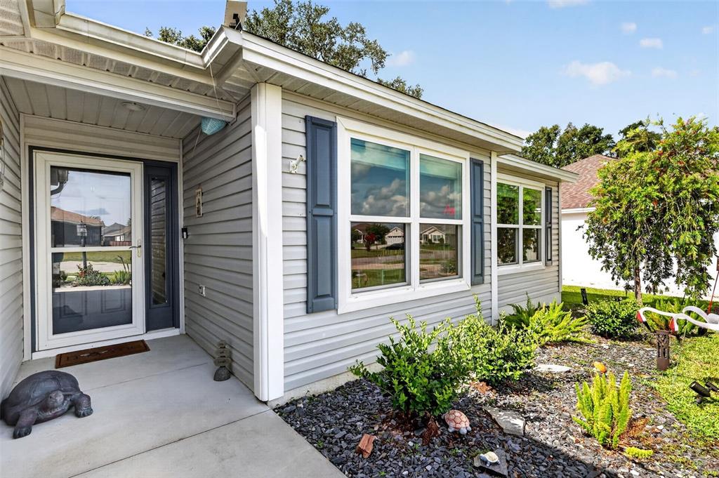 A light gray vinyl-sided house exterior features a white garage door and a front entrance — 11387 ZIMMERMAN PATH, OXFORD, FL