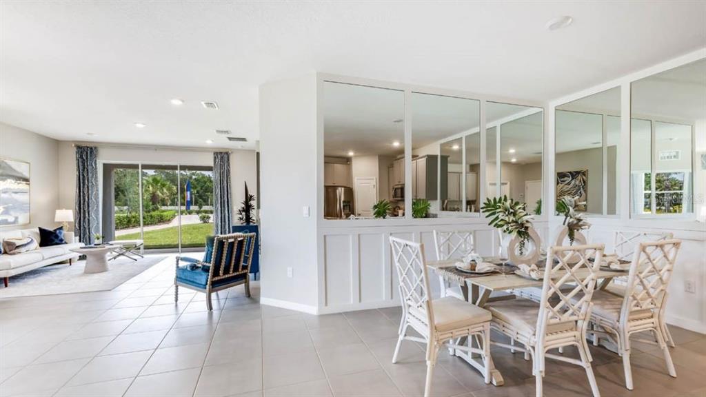 A dining area with a mirrored wall partition overlooks a living room and outdoor patio — 6249 PARMERON LANE, SARASOTA, FL