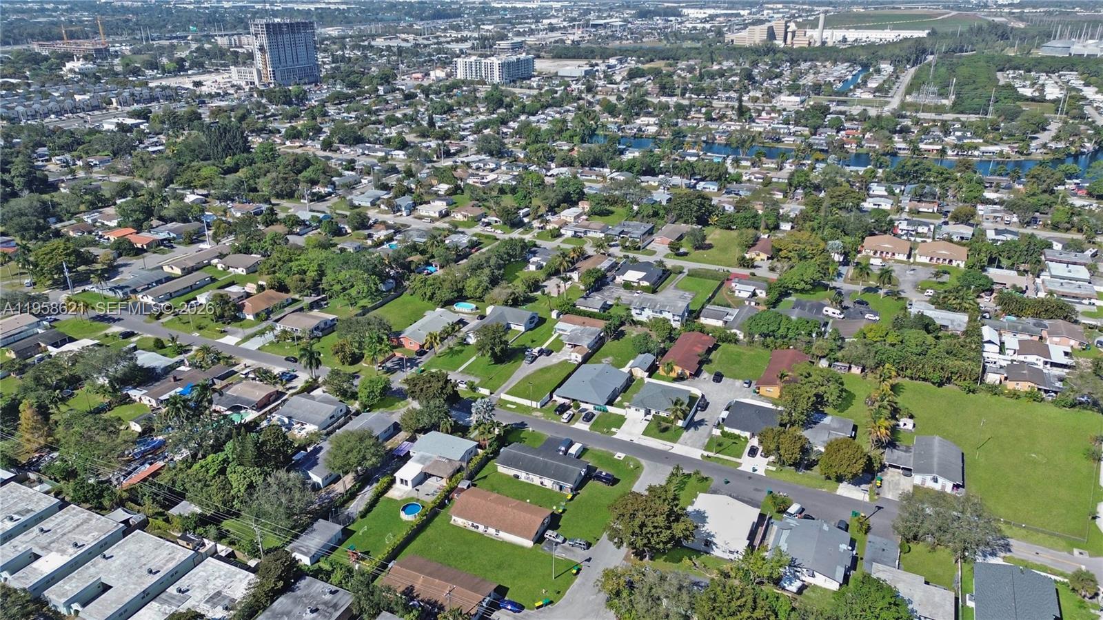 An aerial view shows a suburban neighborhood with houses, green lawns, and nearby water bodies — 4133 SW 52nd St, Dania Beach FL 33314, DANIA BEACH, FL
