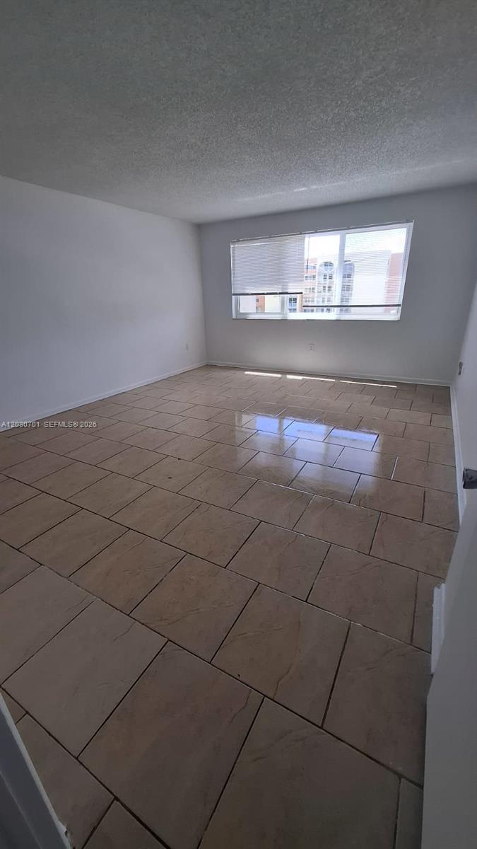 This entryway features beige tiled flooring, a white front door, and white closet doors — 6950 Miami Gardens Dr # 304, Hialeah FL 33015, HIALEAH, FL