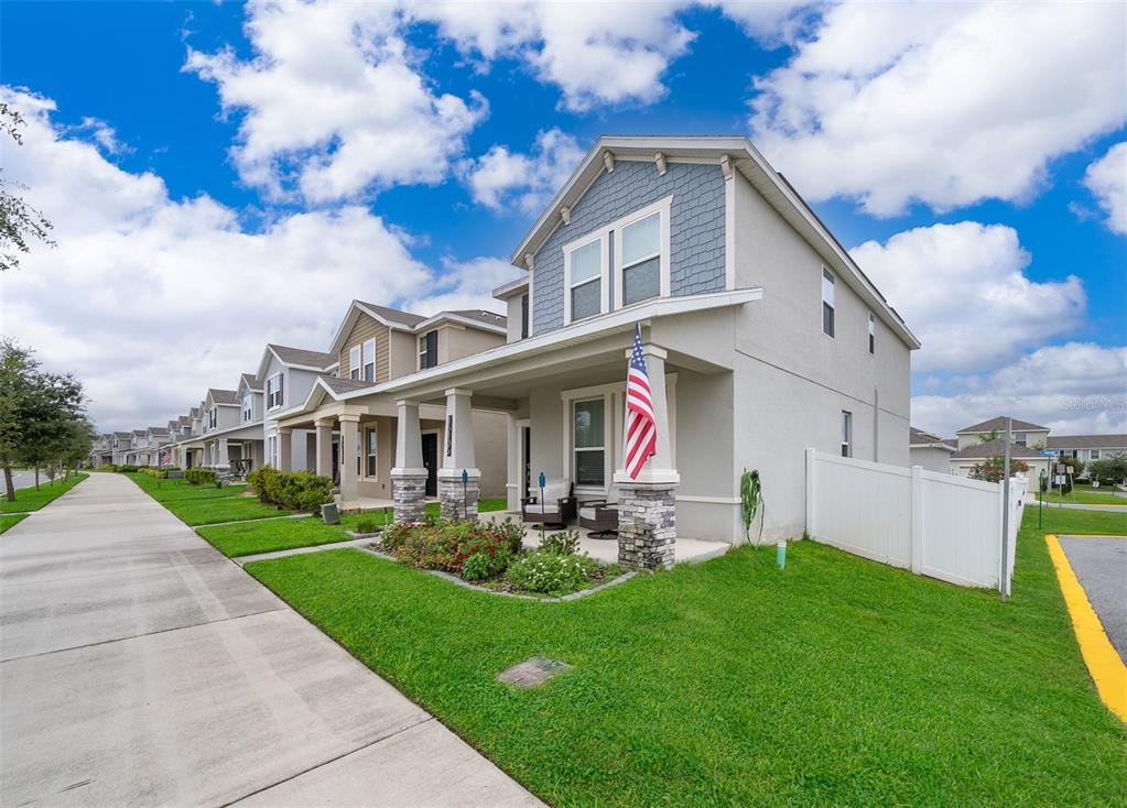 A two-story suburban house with a front porch, stone columns, and an American flag — 16105 WATER SPRING BOULEVARD, WINTER GARDEN, FL