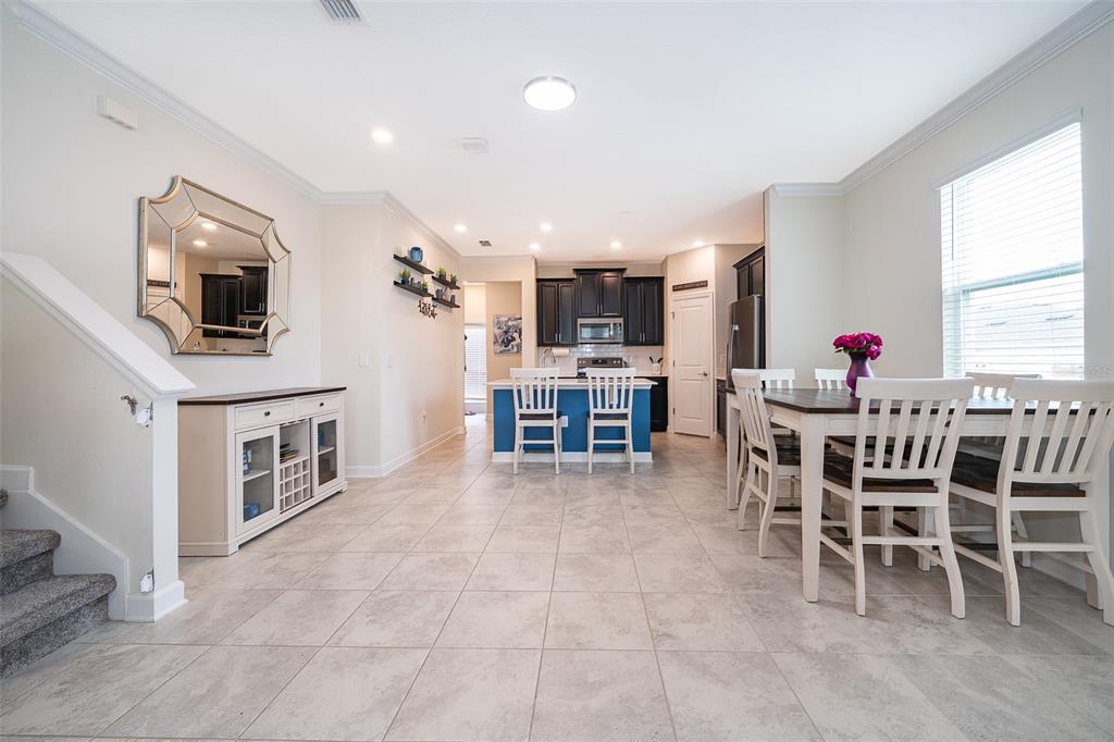 A dining area and kitchen with tile floors, white furniture, and dark cabinetry — 16105 WATER SPRING BOULEVARD, WINTER GARDEN, FL