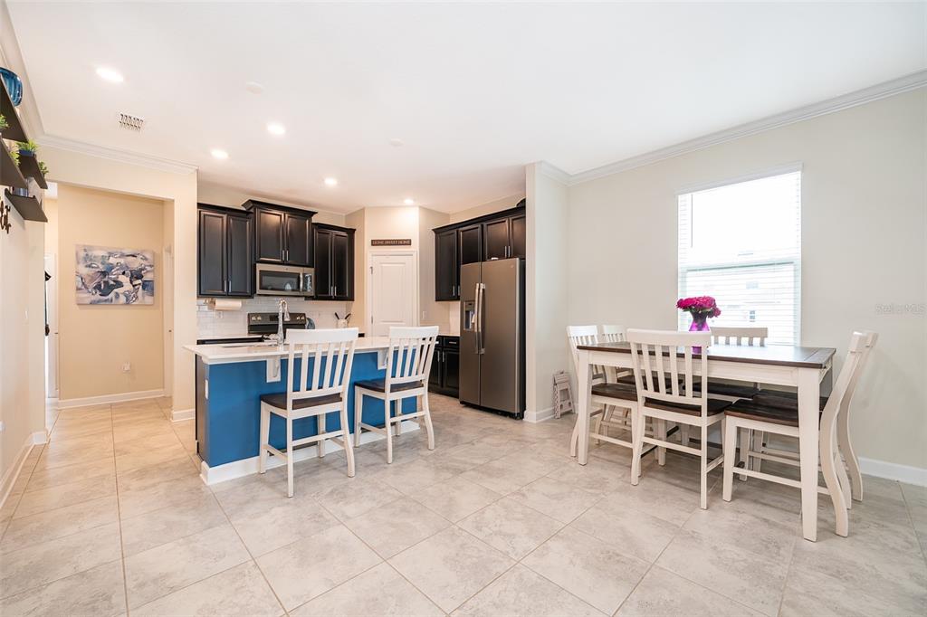A kitchen with dark cabinets, a blue island, and an adjacent dining area with tile floors — 16105 WATER SPRING BOULEVARD, WINTER GARDEN, FL