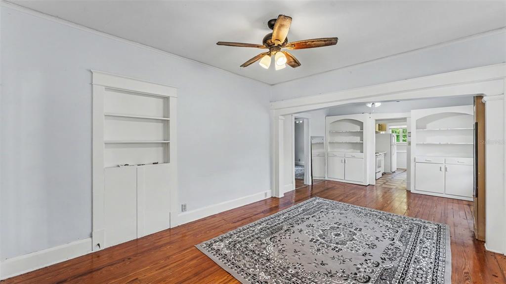 A living room with hardwood floors, a ceiling fan, and built-in white shelving units — 506 S MCKAY AVENUE, LAKELAND, FL
