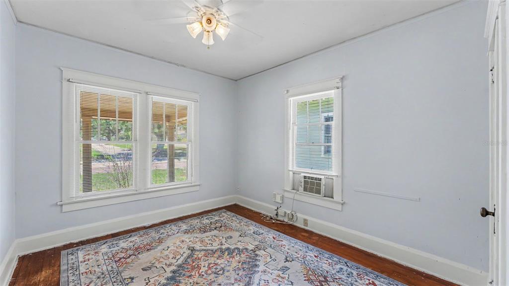 A bedroom with light blue walls, hardwood floors, a ceiling fan, and two windows — 506 S MCKAY AVENUE, LAKELAND, FL