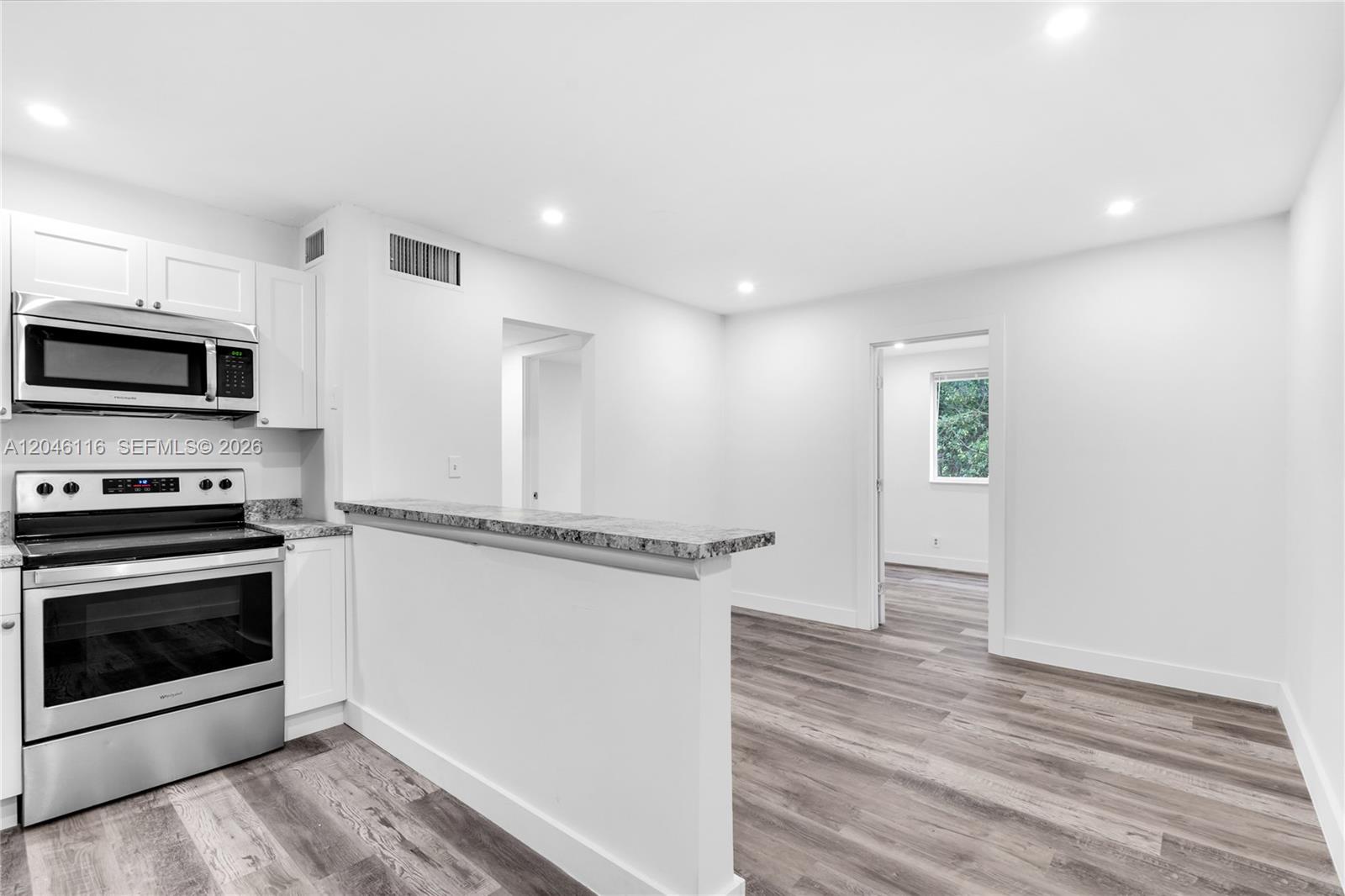 A kitchen with white cabinets, stainless steel appliances, and a granite-topped breakfast bar — 6445 NW 2nd Ave # 19, Miami FL 33150, MIAMI, FL