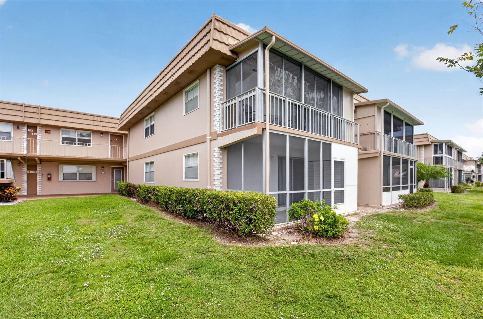 A two-story apartment building with screened-in balconies and a grassy lawn in front — 11 Brittany A, Delray Beach FL 33446, DELRAY BEACH, FL