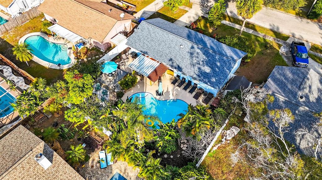 An aerial view shows a house with a blue roof, a swimming pool, and landscaping — 10050 84TH WAY, LARGO, FL