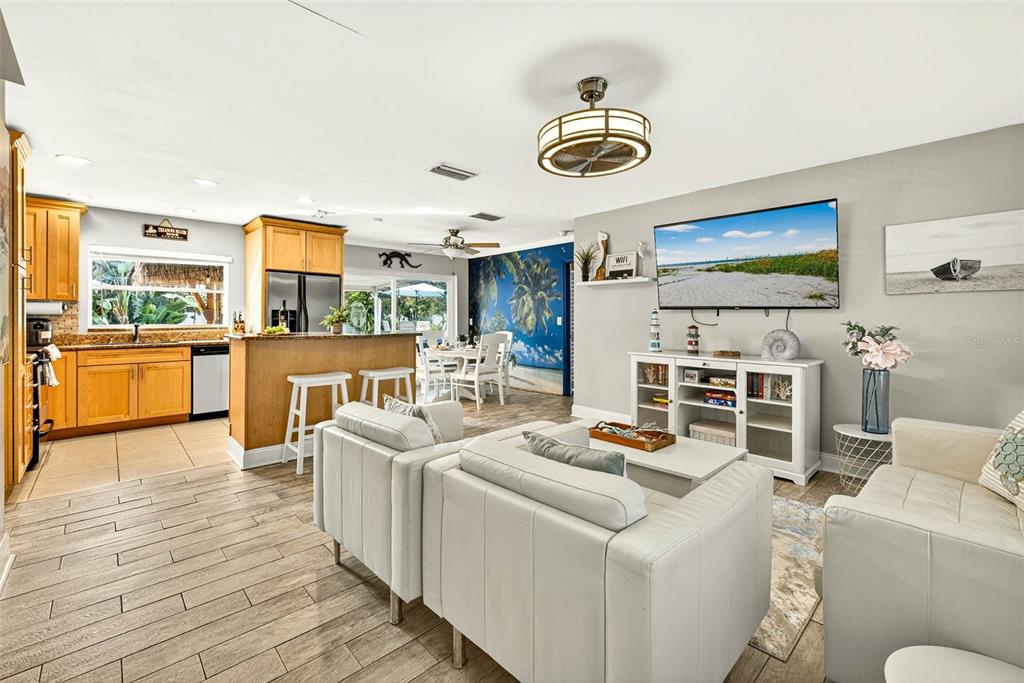An open-concept living room and kitchen featuring light wood cabinets, tile flooring, and white furniture — 10050 84TH WAY, LARGO, FL