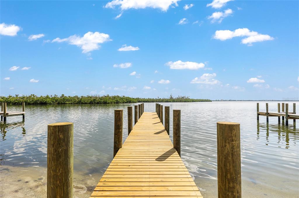 A wooden dock extends into a calm body of water under a bright blue sky — 8178 LITTLE GASPARILLA ISLAND, PLACIDA, FL