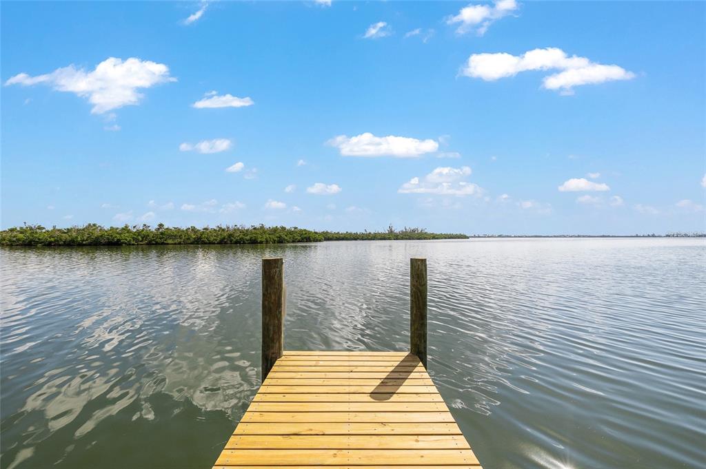 A wooden dock extends into a calm body of water under a blue sky — 8178 LITTLE GASPARILLA ISLAND, PLACIDA, FL