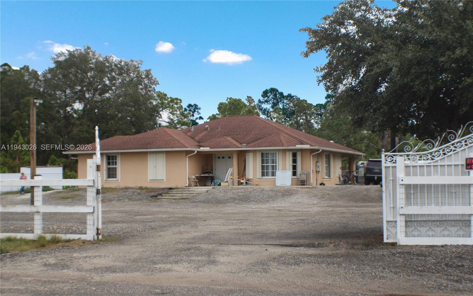 A single-story house with a tan stucco exterior and a brown shingled roof — 355 N Lindero ST, Clewiston FL 33440, CLEWISTON, FL