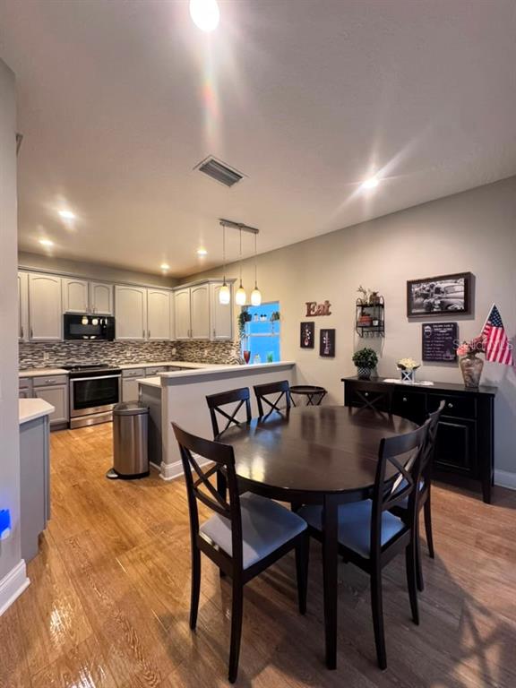 A kitchen with light gray cabinets and a dining area featuring a dark wood table — 6956 BRESCIA WAY, ORLANDO, FL