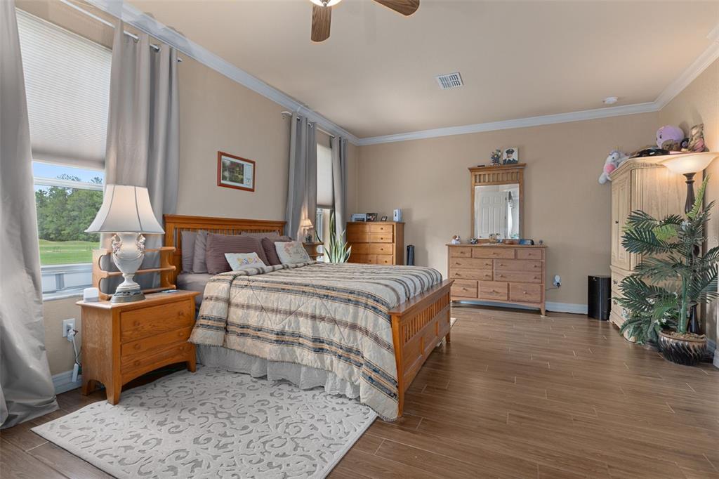 A bedroom features wood-look tile flooring, a wooden bed frame, and a matching dresser set — 5248 ESPLANDE COURT, BROOKSVILLE, FL
