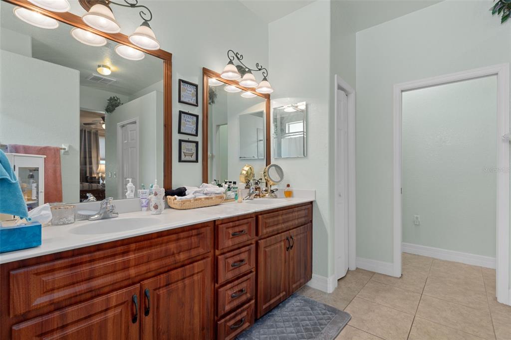 A bathroom features a double vanity with wood cabinets, dual mirrors, and light green walls — 5248 ESPLANDE COURT, BROOKSVILLE, FL