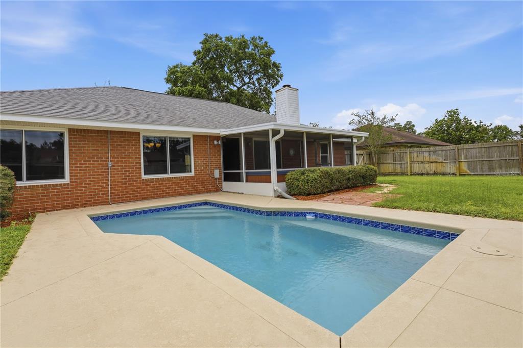 A brick house with a screened porch and a swimming pool in the backyard — 77 BRUNING LANE, PALM COAST, FL