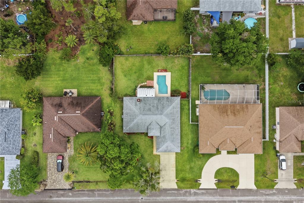 An aerial view shows three suburban houses with pools and driveways along a residential street — 77 BRUNING LANE, PALM COAST, FL