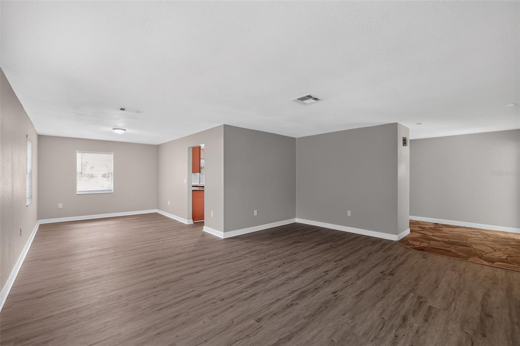 An empty living room features gray walls, wood-look flooring, and a stone-tiled entryway — 2140 N BAY HILLS BOULEVARD, SAFETY HARBOR, FL