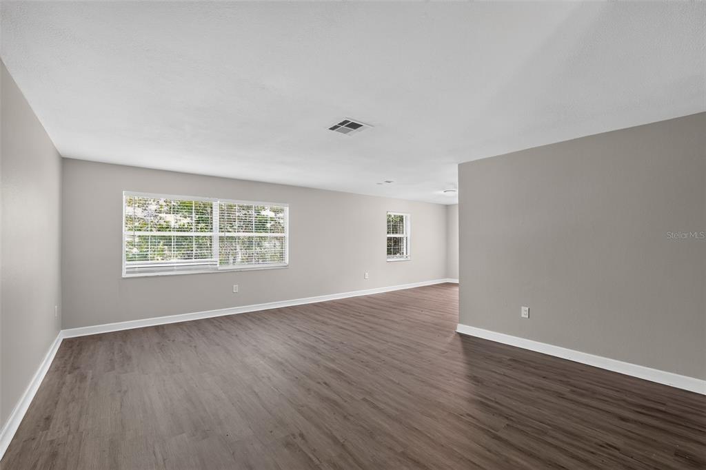 An empty room with light gray walls, dark wood-look flooring, and two windows — 2140 N BAY HILLS BOULEVARD, SAFETY HARBOR, FL
