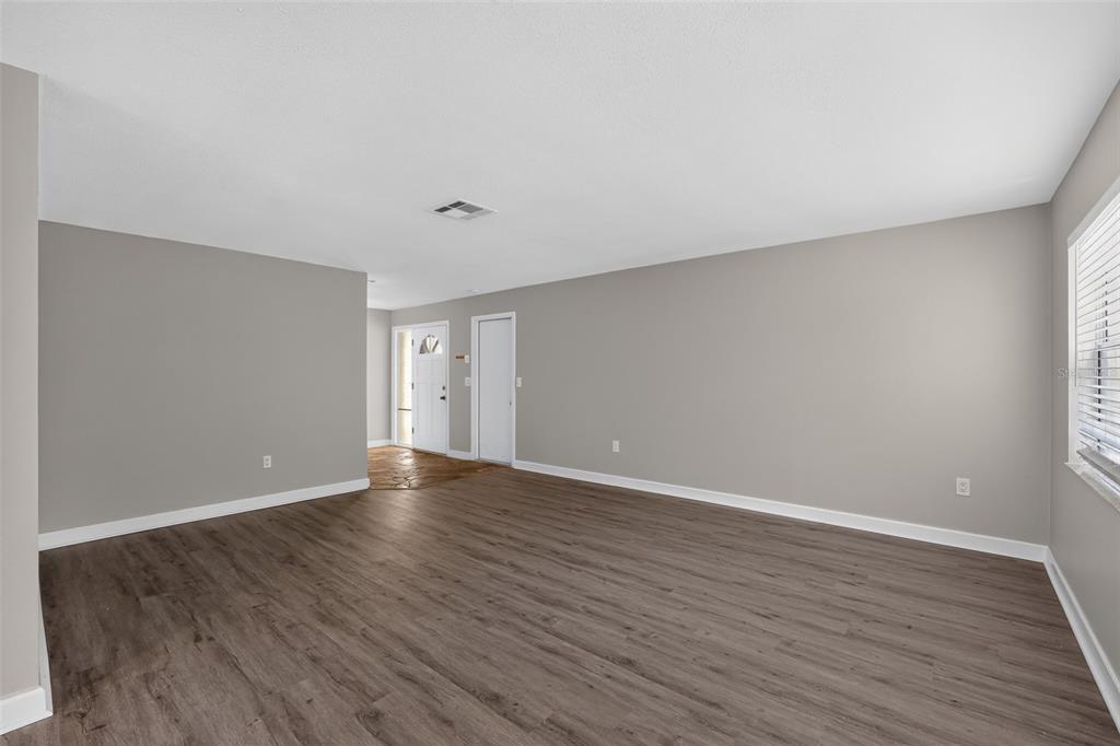 An empty living room with gray walls, wood-look flooring, and a white front door — 2140 N BAY HILLS BOULEVARD, SAFETY HARBOR, FL