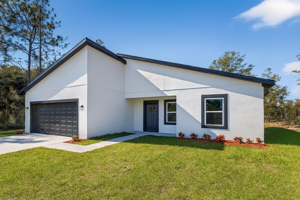A white, single-story house with a dark gray garage door, roof trim, and window frames — 8002 N MALTESE DRIVE, DUNNELLON, FL