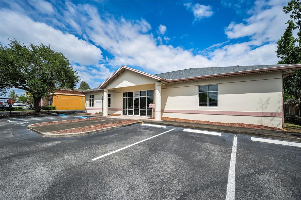 A single-story commercial building with a parking lot in the foreground under a blue sky — 7047 66TH STREET N, PINELLAS PARK, FL