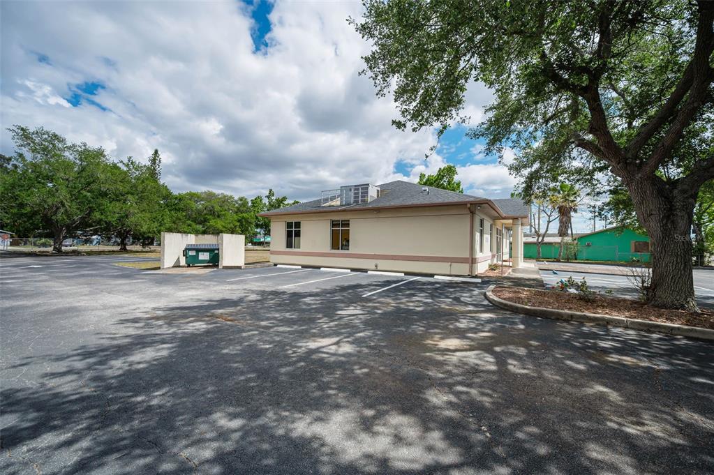 A low-rise commercial building with a parking lot, a dumpster enclosure, and mature trees — 7047 66TH STREET N, PINELLAS PARK, FL
