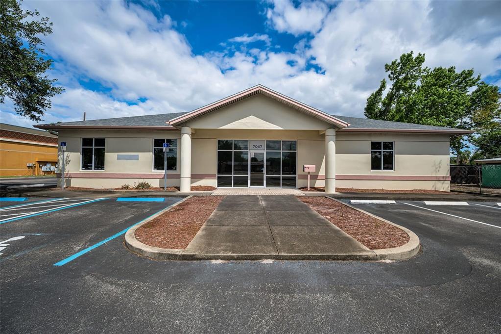 A single-story commercial building with a central entrance, columns, and a paved parking lot — 7047 66TH STREET N, PINELLAS PARK, FL