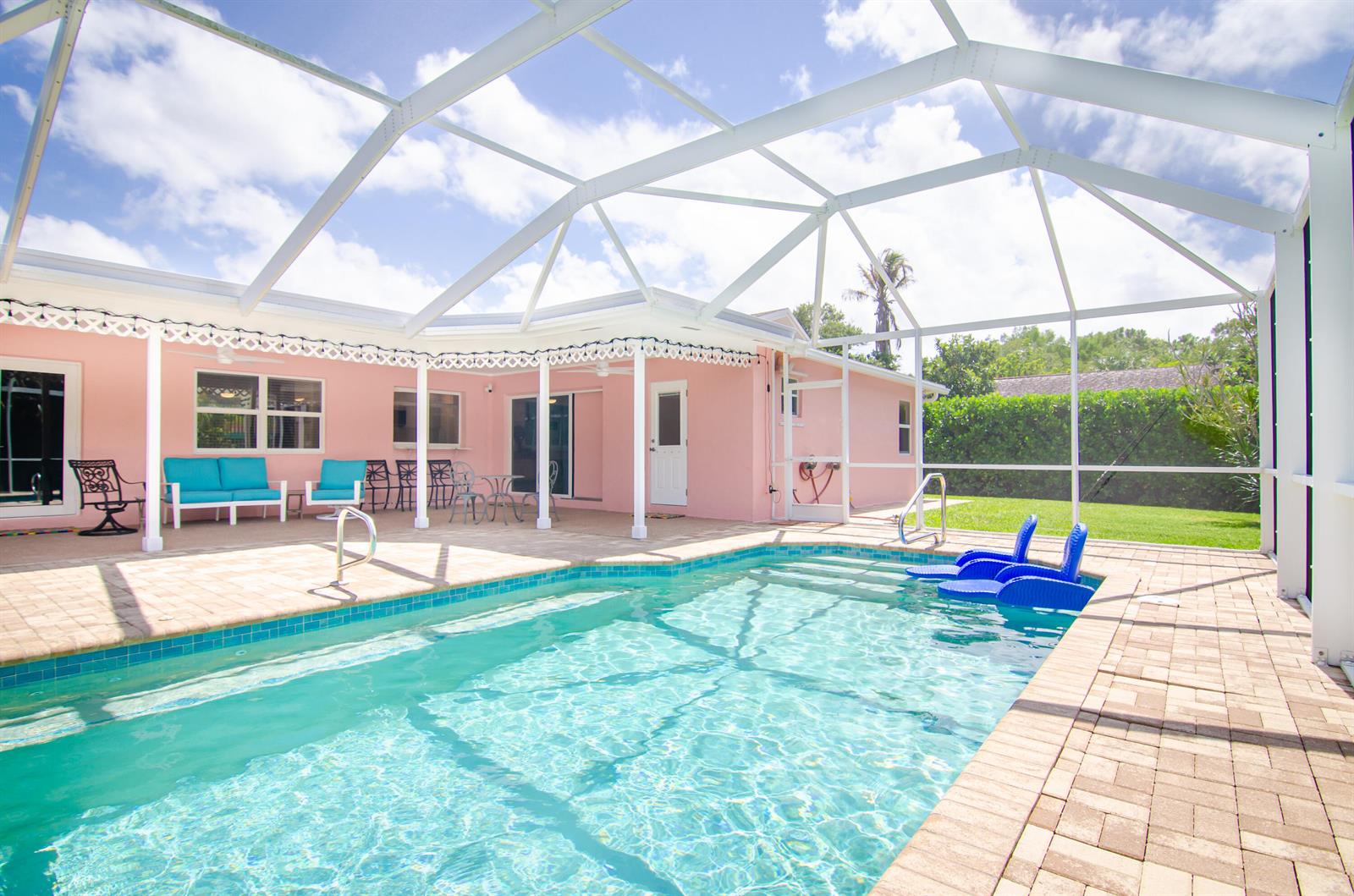 A pink house with a screened-in pool and patio area under a white frame enclosure — 613 Oak Terrace, Jupiter FL 33458, JUPITER, FL