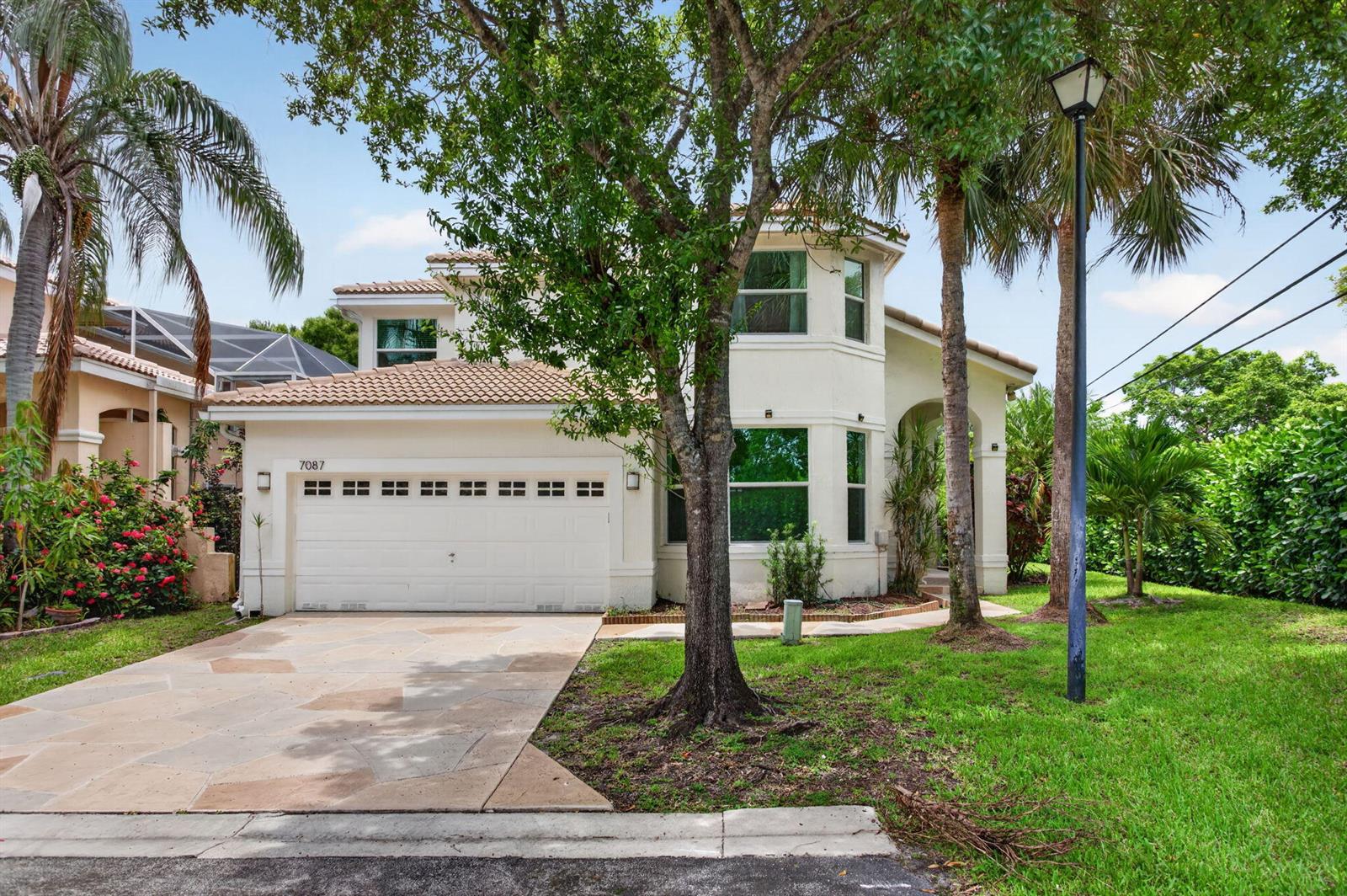 A two-story house with a white stucco exterior, a tile roof, and a paved driveway — 7087 NW 78th Place, Parkland FL 33067, PARKLAND, FL