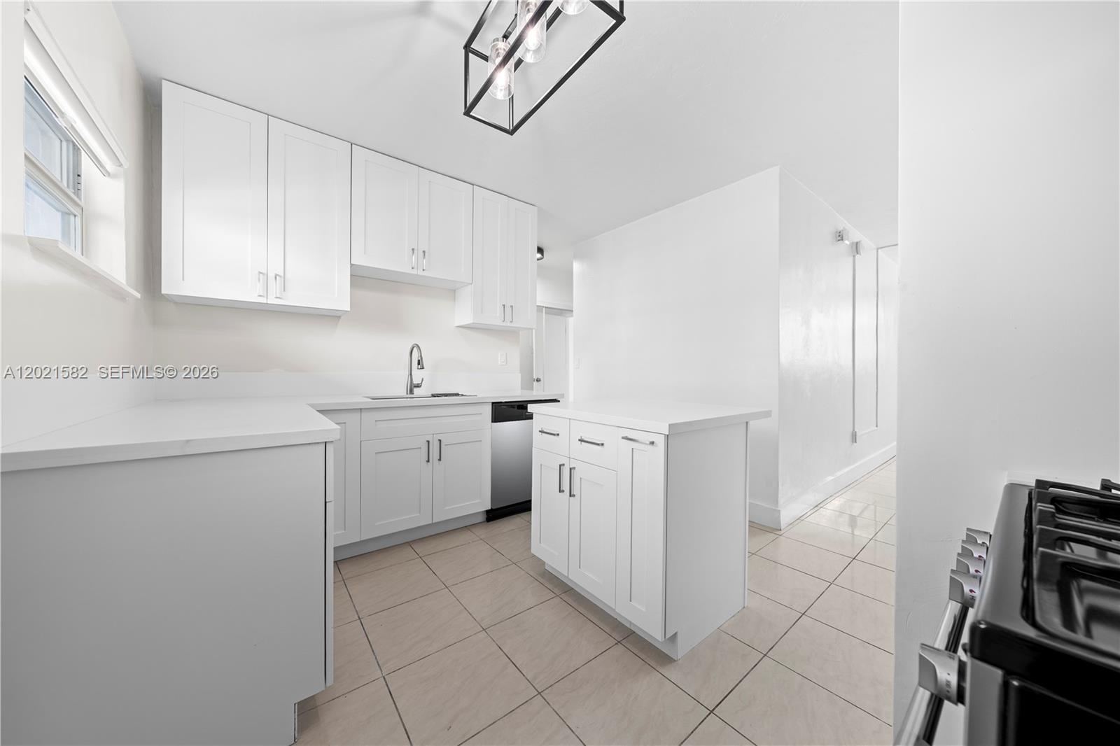 A modern kitchen features white cabinets, stainless steel appliances, and a central island — 1300 Lincoln Rd # D204, Miami Beach FL 33139, MIAMI BEACH, FL